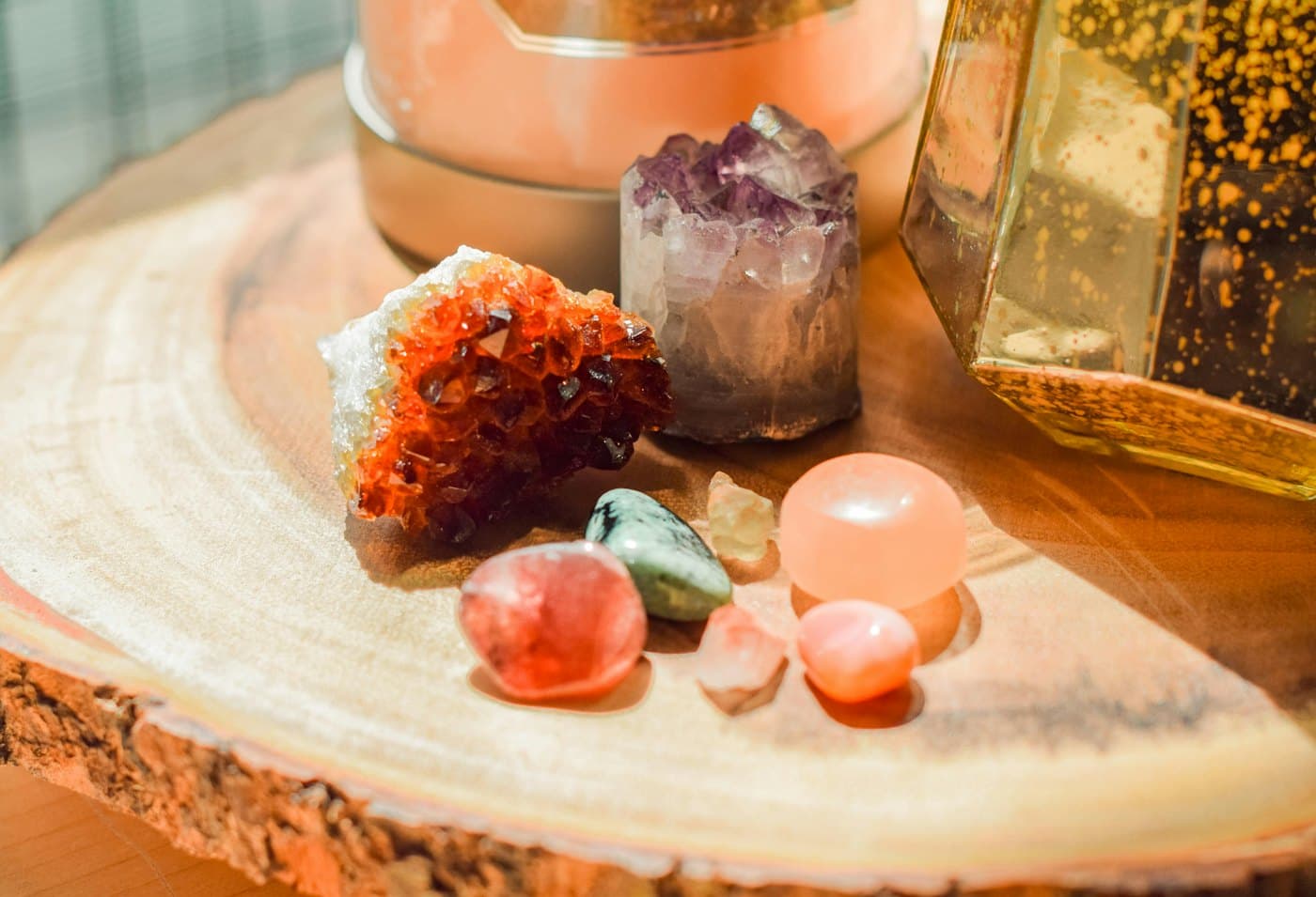 A styled table of stones, a citrine cluster and a lit candle on a wooden board